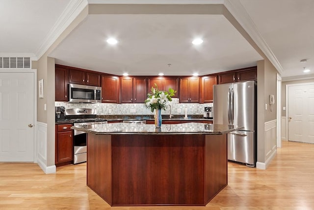 4 Sterling Hill Ln Unit 424, Exeter, NH 03833 - kitchen with appliances with stainless steel finishes, ornamental molding, light wood finished floors, a kitchen island, and decorative backsplash