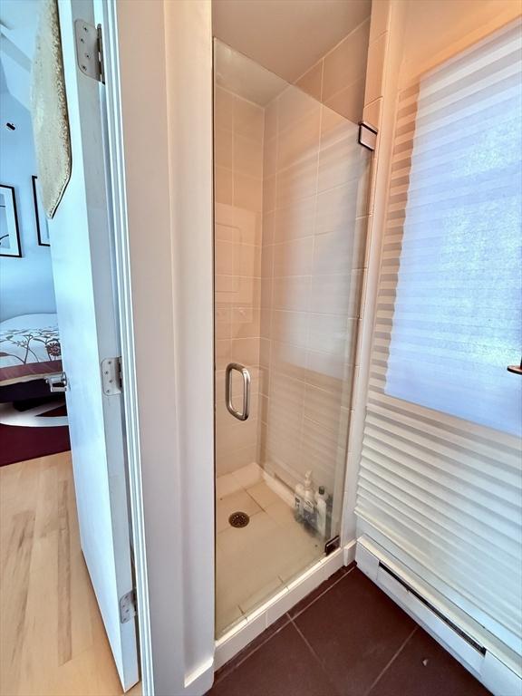 full bath featuring ensuite bath, a stall shower, tile patterned floors, and a baseboard radiator