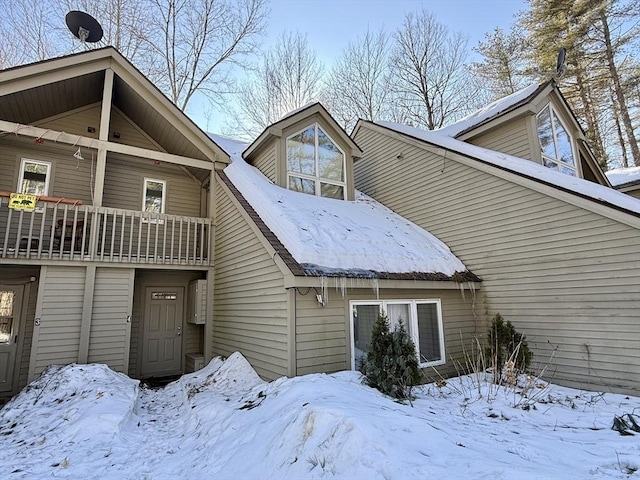 snow covered house featuring a balcony