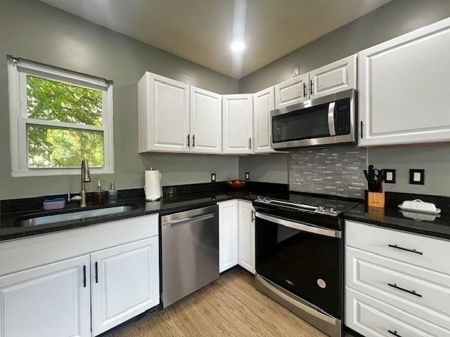 36 Circle St, Templeton, MA 01436 - kitchen with stainless steel appliances, a sink, white cabinetry, light wood-type flooring, and decorative backsplash