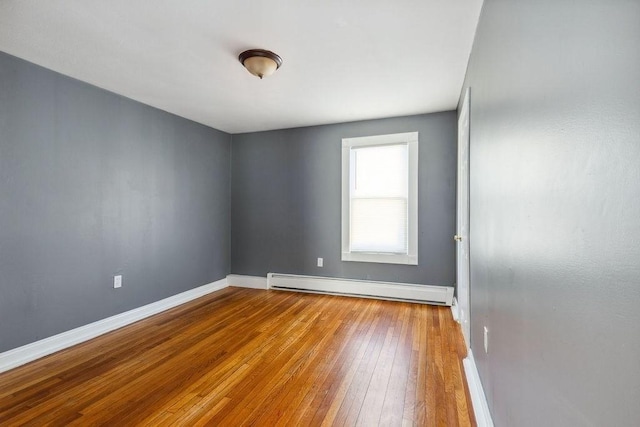 spare room with wood-type flooring and a baseboard heating unit