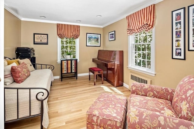 sitting room featuring baseboards, radiator, ornamental molding, recessed lighting, and light wood-style flooring