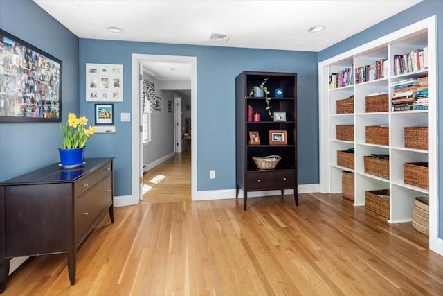 sitting room featuring visible vents, light wood-style flooring, and baseboards