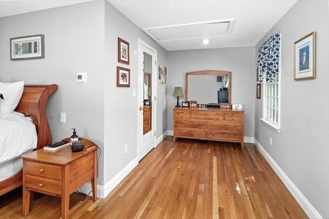 corridor with baseboards, attic access, and wood finished floors