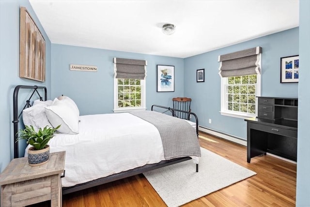 bedroom with baseboards, baseboard heating, and wood finished floors