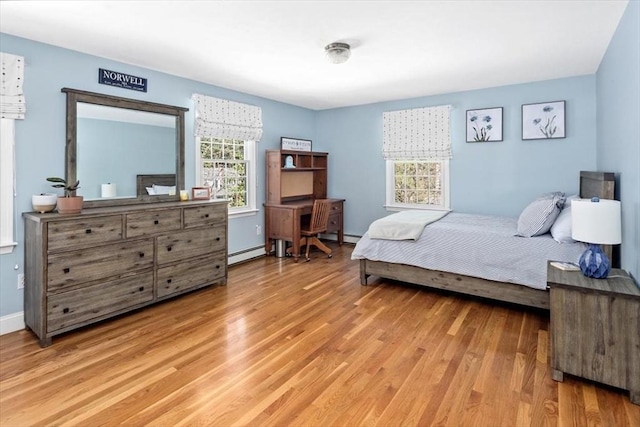 bedroom featuring light wood-style floors, baseboards, and a baseboard heating unit