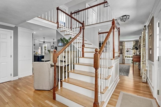 staircase featuring baseboards, ornamental molding, and wood finished floors