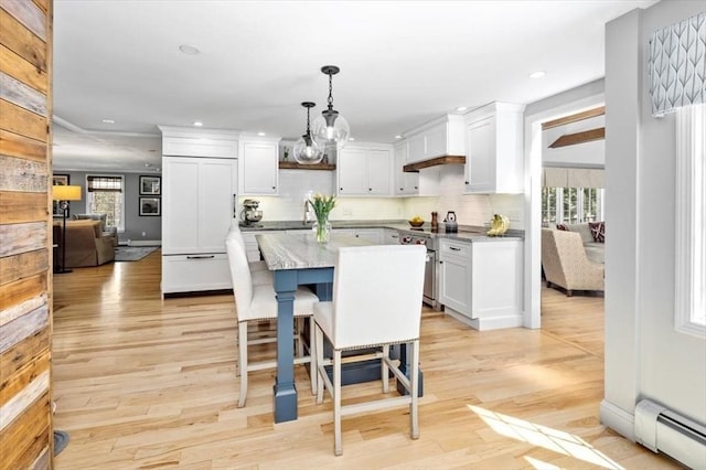 kitchen with paneled built in fridge, a baseboard radiator, a wealth of natural light, and stainless steel range with electric cooktop