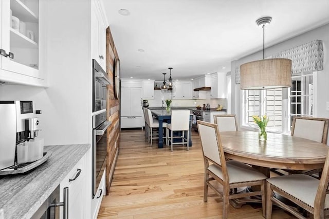 dining area featuring recessed lighting, light wood finished floors, and an inviting chandelier