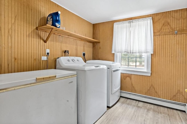 laundry room featuring independent washer and dryer, light wood-style flooring, a baseboard heating unit, wood walls, and laundry area