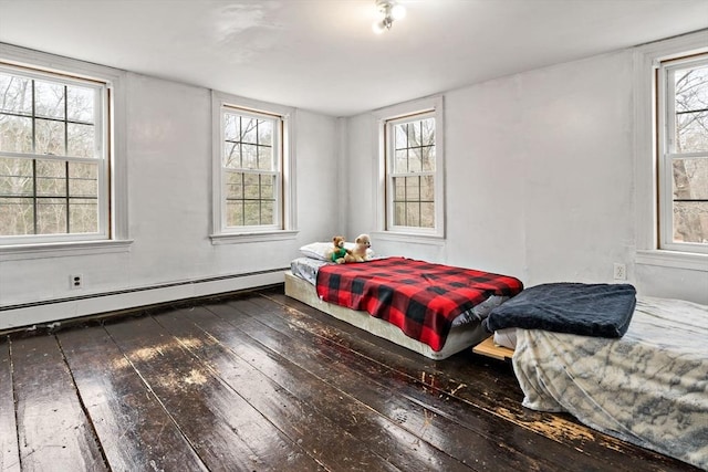 bedroom with multiple windows, wood-type flooring, and a baseboard radiator