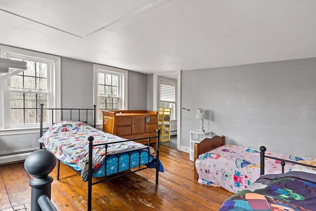 bedroom with a baseboard radiator, baseboards, and hardwood / wood-style floors