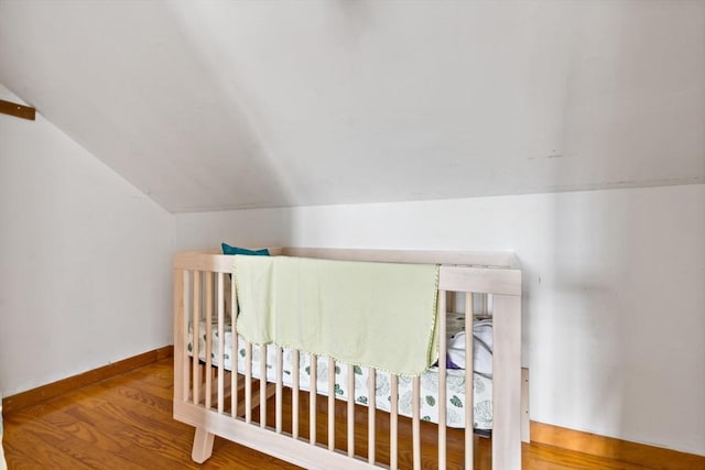 bedroom with baseboards, lofted ceiling, and wood finished floors