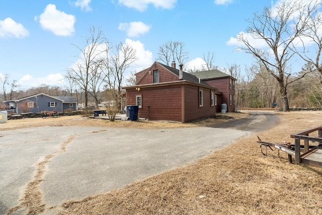 view of side of home featuring a chimney and driveway