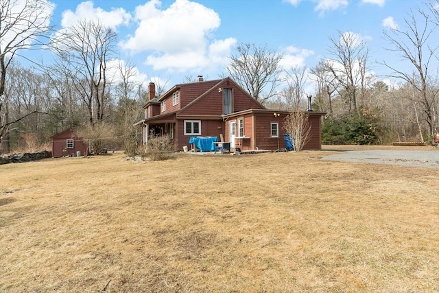 view of property exterior featuring an outbuilding, a chimney, and a yard