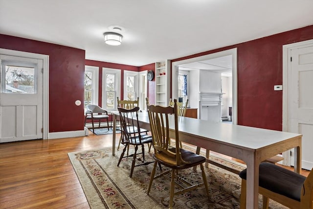 dining room featuring a fireplace, baseboards, and hardwood / wood-style flooring