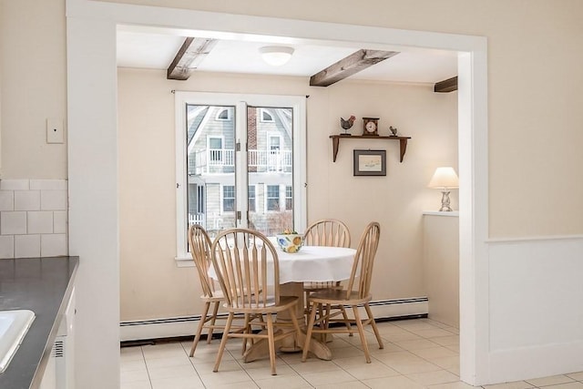 tiled dining room with a baseboard heating unit, sink, and beamed ceiling