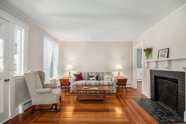 living room with a baseboard heating unit, hardwood / wood-style flooring, ornamental molding, and a brick fireplace