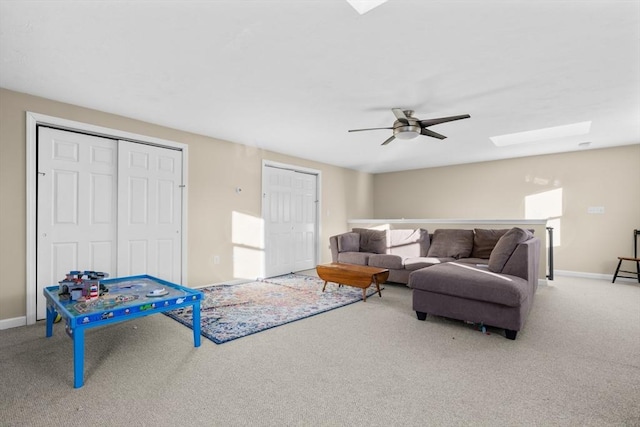 living room with a skylight, carpet flooring, and ceiling fan