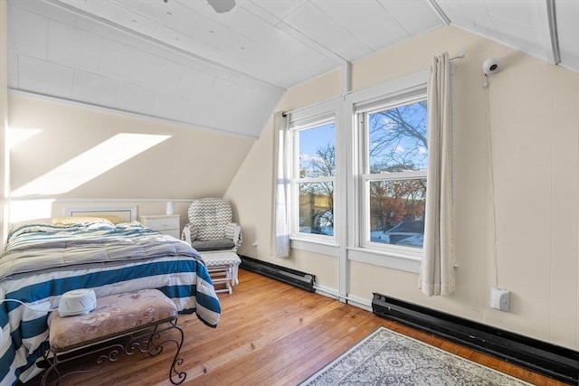 bedroom with hardwood / wood-style floors, vaulted ceiling, and a baseboard heating unit