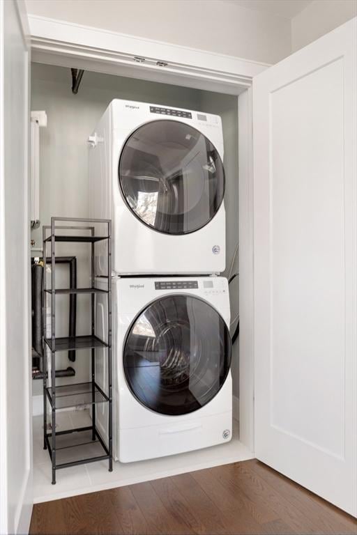 washroom featuring stacked washing maching and dryer, laundry area, and wood finished floors