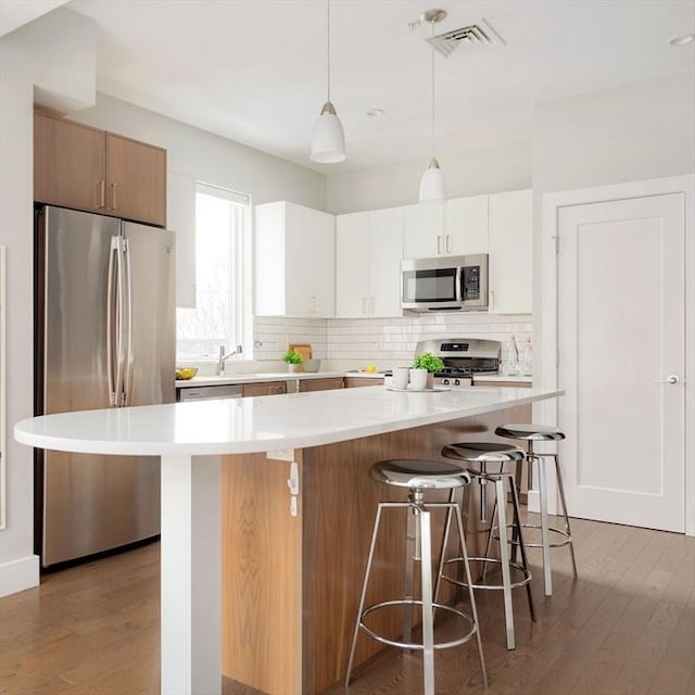 kitchen featuring a center island, light countertops, visible vents, appliances with stainless steel finishes, and white cabinetry