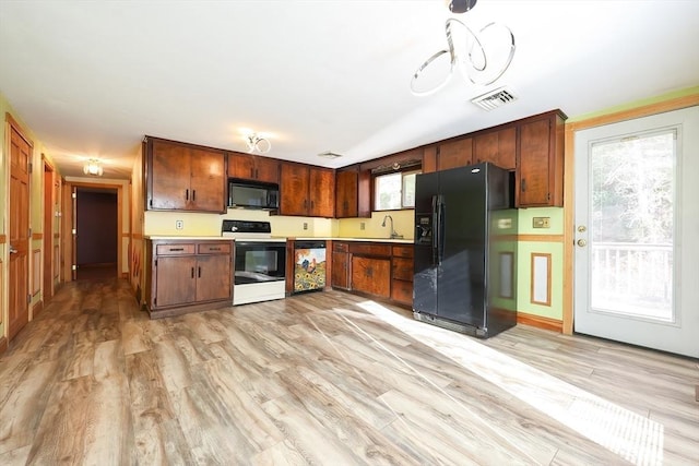 kitchen featuring black appliances, sink, and light hardwood / wood-style flooring