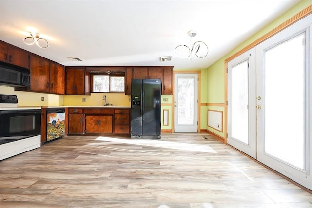 kitchen with a chandelier, sink, a wealth of natural light, and black appliances