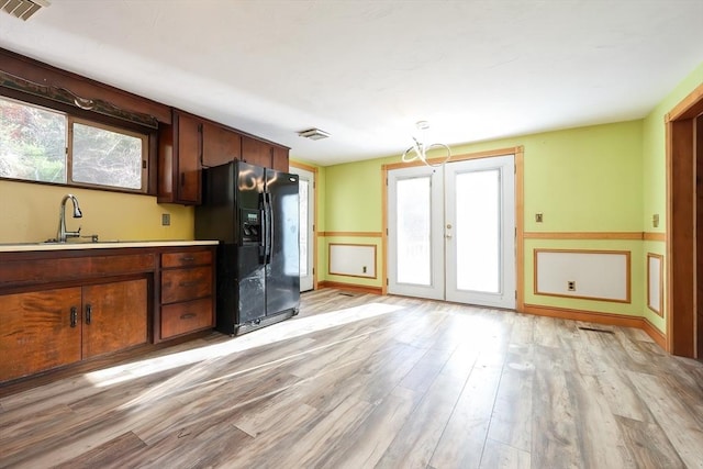 kitchen featuring black fridge with ice dispenser, french doors, light hardwood / wood-style flooring, and a wealth of natural light