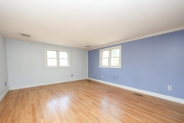 empty room featuring plenty of natural light, light hardwood / wood-style floors, and ornamental molding