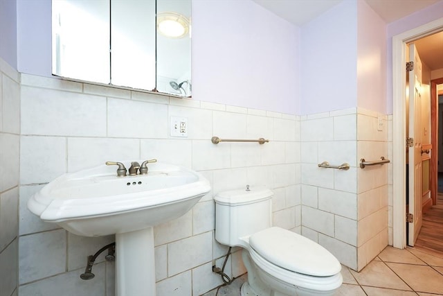 bathroom with tile patterned flooring, toilet, and tile walls