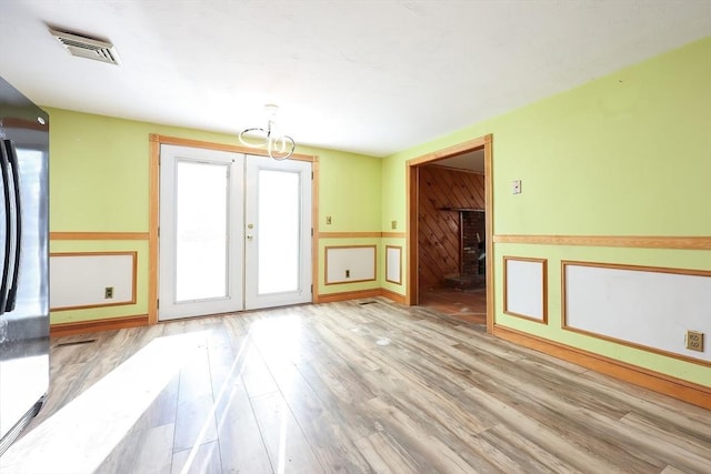 empty room with light hardwood / wood-style floors and french doors