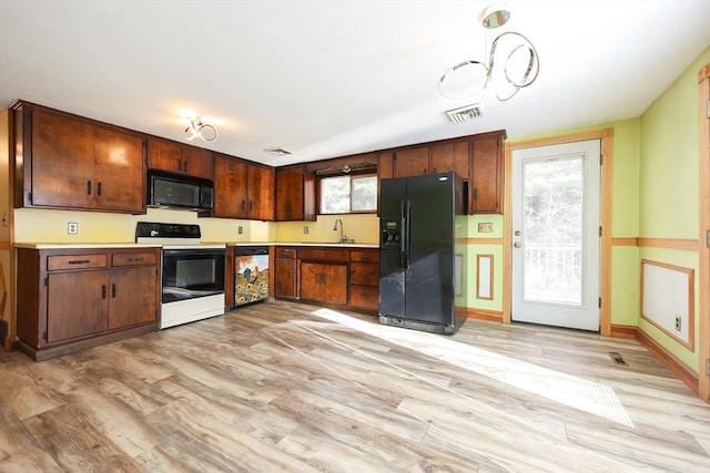 kitchen featuring black appliances, plenty of natural light, pendant lighting, and light wood-type flooring