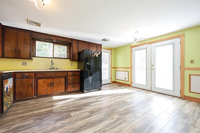 kitchen featuring french doors, light wood-type flooring, black fridge with ice dispenser, sink, and dishwasher