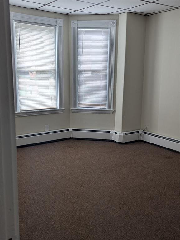 spare room featuring a drop ceiling and dark carpet