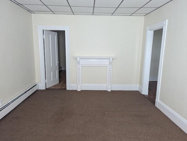 empty room featuring a baseboard radiator, a drop ceiling, dark carpet, and baseboards