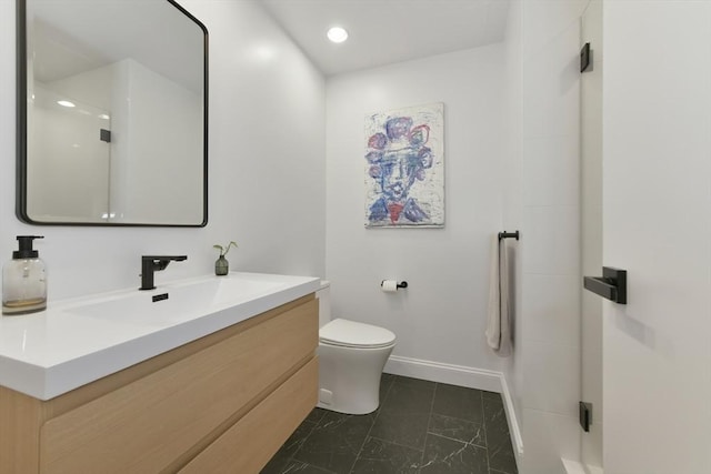 bathroom with a shower, vanity, toilet, and baseboards