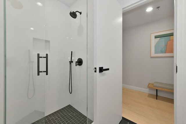 full bathroom featuring a tile shower, baseboards, and wood finished floors