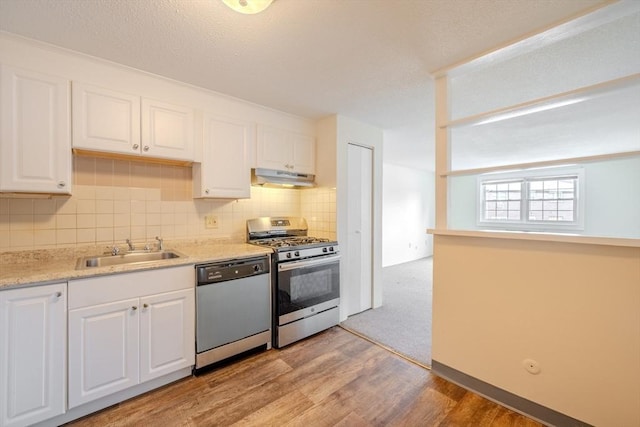 kitchen featuring sink, white cabinetry, light hardwood / wood-style flooring, appliances with stainless steel finishes, and backsplash