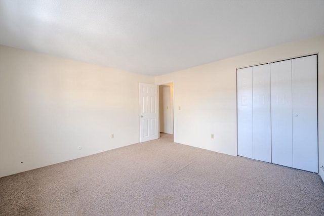 unfurnished bedroom with light colored carpet and a closet