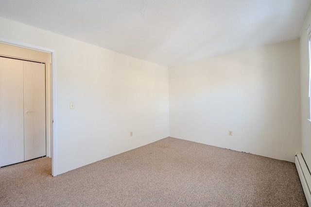 unfurnished room featuring light carpet and a baseboard heating unit