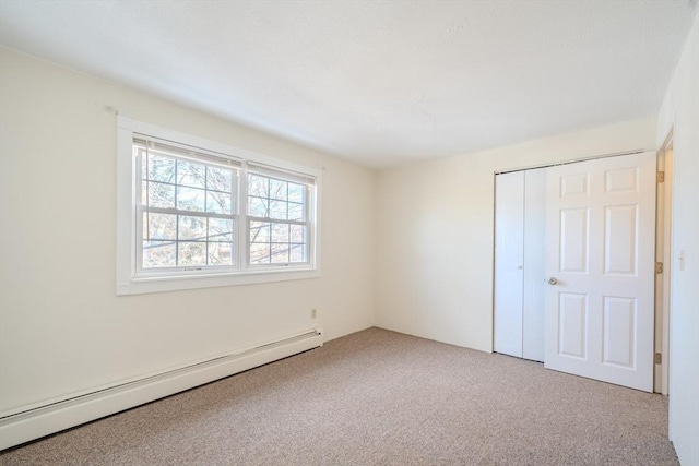 unfurnished bedroom with light carpet, baseboard heating, and a closet