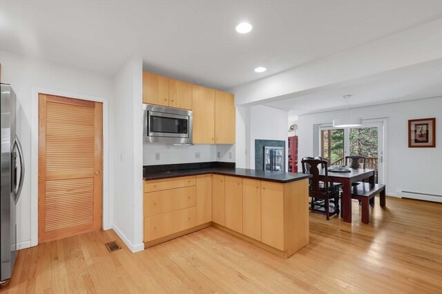 kitchen featuring light brown cabinetry, appliances with stainless steel finishes, light wood-style floors, and a peninsula