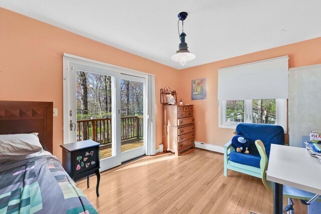 bedroom featuring access to outside, baseboards, a baseboard heating unit, and light wood-type flooring