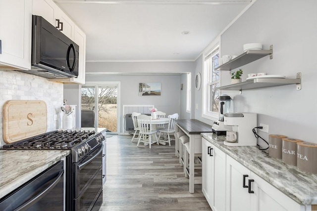 1 Ladd Ave, Wareham, MA 02571 - kitchen with black microwave, double oven range, white cabinets, tasteful backsplash, and light stone countertops