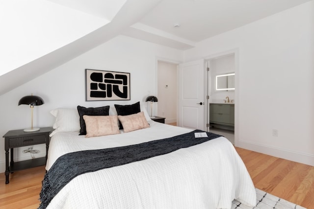 bedroom with wood-type flooring and ensuite bath