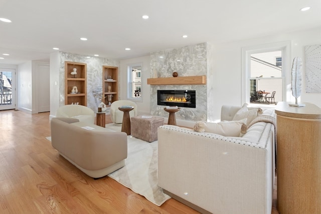 living room with a high end fireplace and light hardwood / wood-style flooring