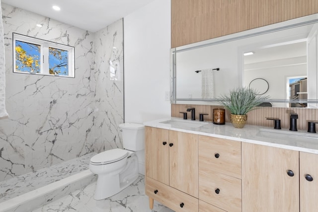 bathroom featuring a tile shower, vanity, and toilet