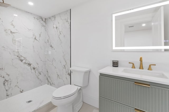 bathroom featuring a tile shower, vanity, and toilet