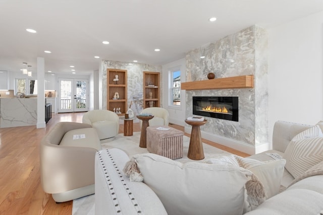 living room featuring a large fireplace, french doors, and light hardwood / wood-style flooring